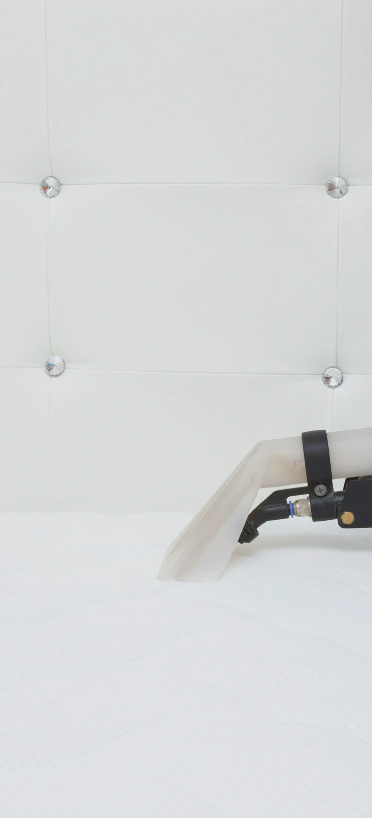 Zbliżenie na&nbsp;czyszczenie białego, pikowanego zagłówka łóżka